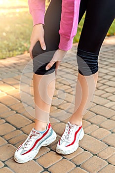 Healthy Lifestyle. Young woman standing holding knee outdoors autumn season close-up