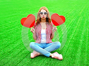 young woman makes an air kiss with red balloon in the shape of a heart