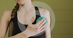 Young woman makes a self-massage shoulder ball for a myofascial release. Muscle relaxation, self-massage