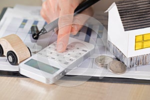 Young woman makes some calculations. Small paper house, coins, c photo