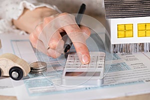 Young woman makes some calculations. Small paper house, coins, c photo