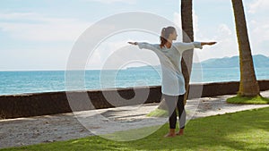 Young woman makes yoga practice on the beach near calm ocean on island Bali with beautiful background