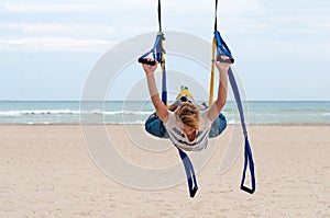 Young woman making antigravity yoga. fly-yoga exercises with yellow, blue hammock on sea background. Healthy life