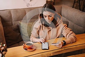 Young woman making card payment through mobile phone to pay bills.