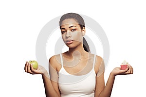 Young woman making choice, sweets or apple isolated