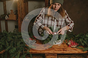 Young woman making Christmas floral arrangement for winter home decor.