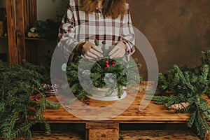 Young woman making Christmas table decoration for winter interior decor.