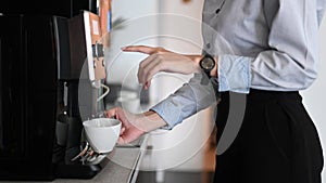 Young woman making coffee with coffee machine during office break time.