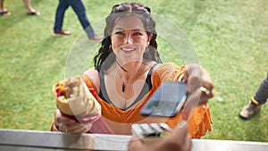 Young Woman Making Contactless Payment At Food Van At Outdoor Festival