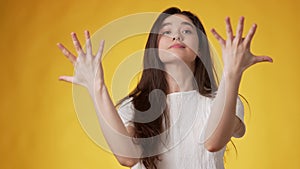 Young woman making distressing gestures against yellow background