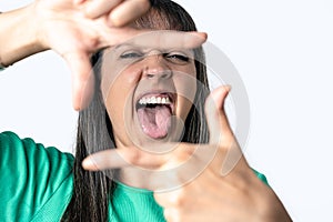 Young woman making a frame with her fingers and sticking out her tongue