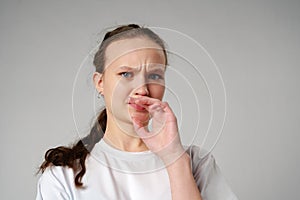 Young Woman Making Funny Face With Her Fingers on gray background