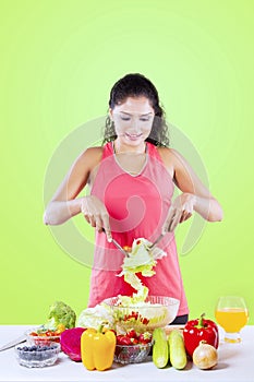 Young woman making healthy salad on studio