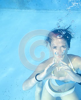 Young woman making heart symbol with her hands underwater