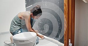 Young woman making home repair covers baseboard with masking tape
