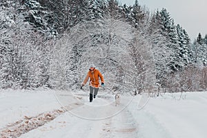 Young woman making a morning run with a husky puppy in the winter forest