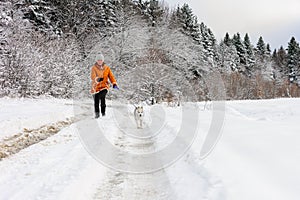 Young woman making a morning run with a husky puppy in the winter forest