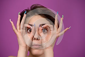 Young woman making ok gesture like binoculars with hands