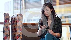 Young woman making online purchases using credit card and phone