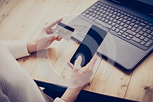 Young woman making online shopping by laptop and smartphone.Girl touching home button on mobile phone, writing security