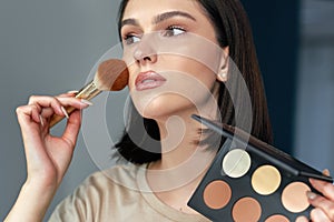 Young woman making an online tutorial and showing her favorite organic beauty product. A female doing makeup herself