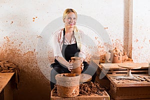 Young woman making pot using pottery wheel