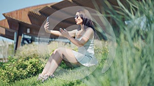 Young woman making selfie sitting on green grass