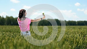 Young woman making selfies in green wheat field