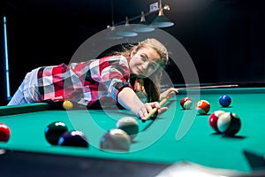 Young woman making shot in billiard