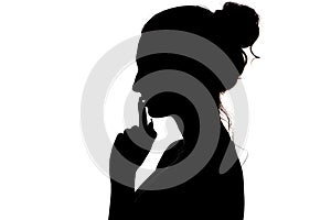 Young woman making a sign by finger near lips that means silence or secret, silhouette profile of unknown girl with a bun, privacy