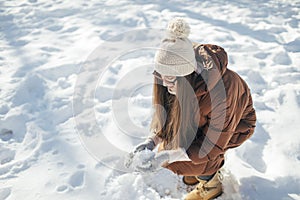 Young woman making snowball outdoors