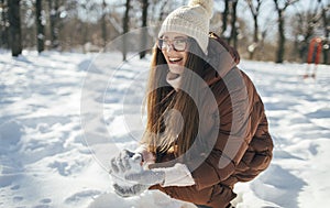 Young woman making snowball outdoors in the winter park
