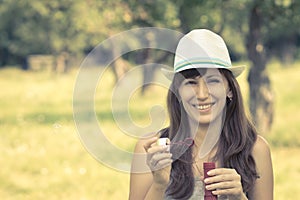 Young woman making soap bubbles in summer park.