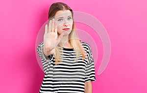 Young woman making a stop pose on a pink background