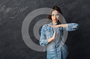 Young woman making time out sign at gray background