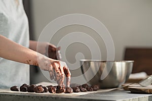 Young woman making truffles candy on kitchen