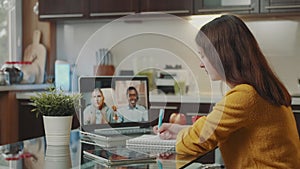 Young woman making video call with two multiracial colleagues on computer