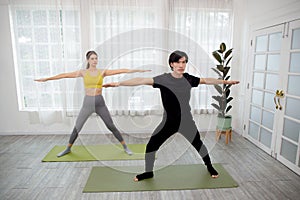 Young woman and man doing yoga with stretch muscles leg and hands at home.