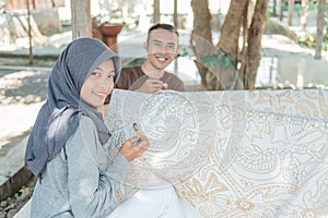 Young woman and man drawing batik