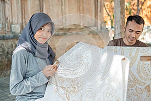 Young woman and man drawing batik