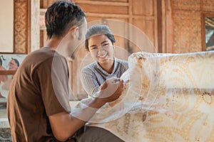 Young woman and man drawing batik on a white cloth