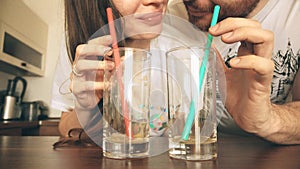 Young woman and man drinking juice with straws together. Healthy lifestyle or funny competition concepts