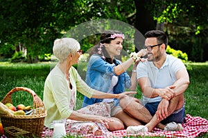 Young woman and man with grandmother smilling in a park on a sunny day