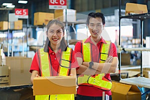 Young woman and man holding cardboard package working in warehouse among racks and shelves prepare for service moving delivering
