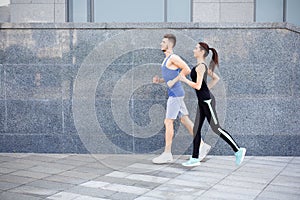 Young woman and man jogging in city copy space