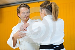 Young woman and man judo fighters in sport hall
