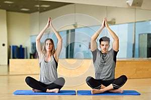 Young woman and man practicing yoga indoors