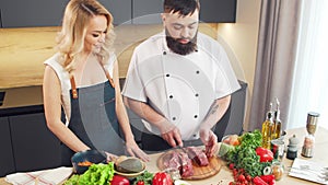 Young woman and man prepare food and host a cooking show. The bloggers stream from kitchen. Healthy food preparation.