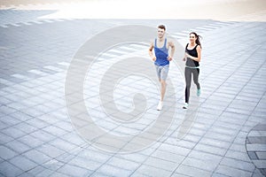 Young woman and man running in city copy space