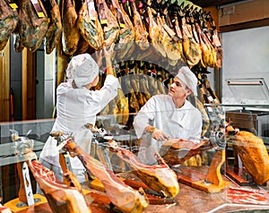Young woman and man selling ham in jamoneria